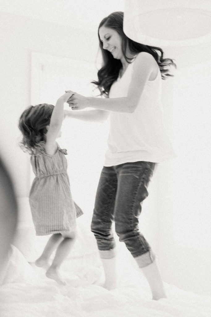 Mom and daughter jumping on bed in black and white by Niagara photographer