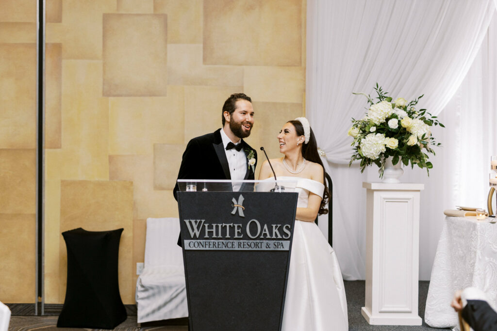 Bride & Groom laughing while giving speech at wedding reception at White Oaks in Niagara on the lake by St. Catharines Photographer