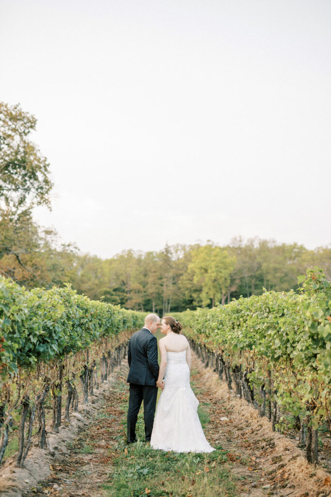 Wedding Couple Walking through vineyard at sunset photos at Riverbend Inn 