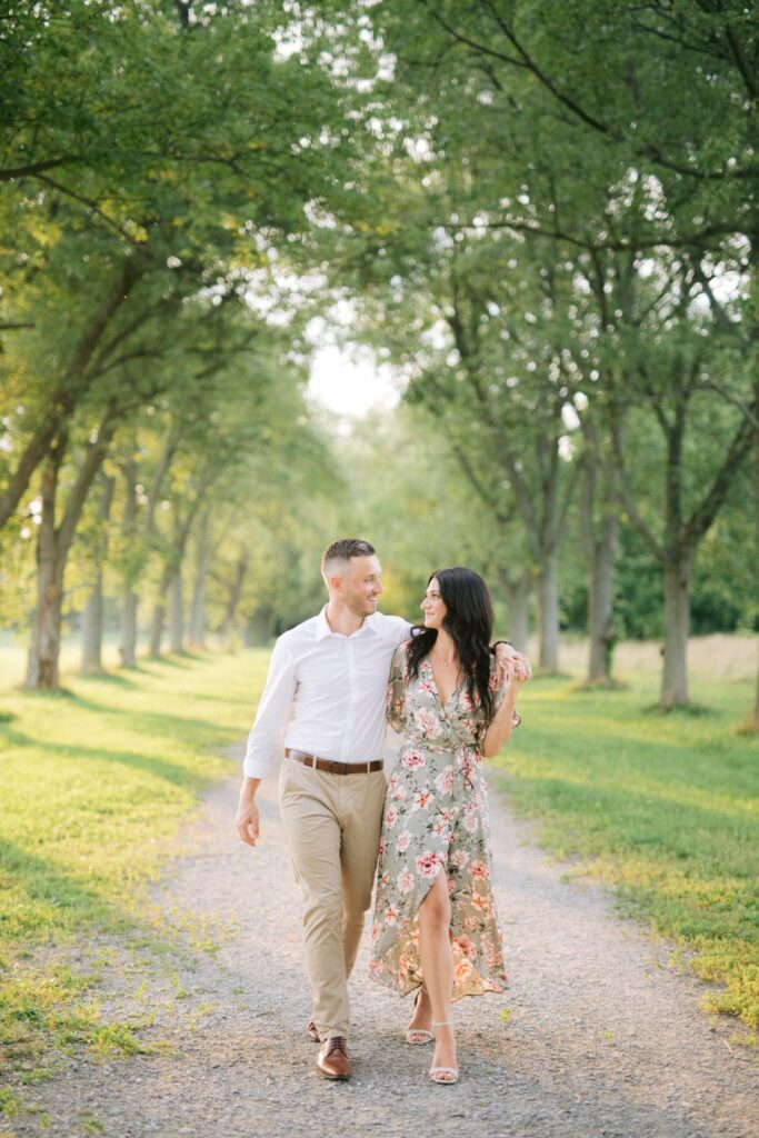 Couple Walking Down Tree Lined Path At Sunset for Engagement Photos taken by Niagara on the lake photographer