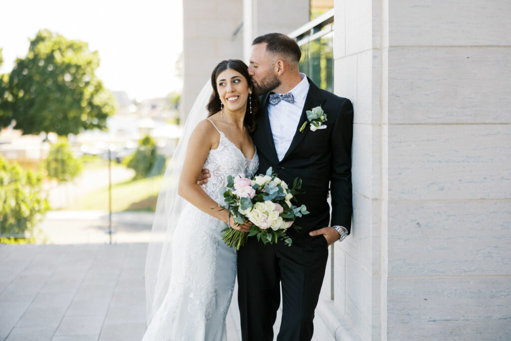 Groom Kissing Bride on forehead during portraits at the Pearle Hotel on Wedding day in Burlington by Niagara Photographer