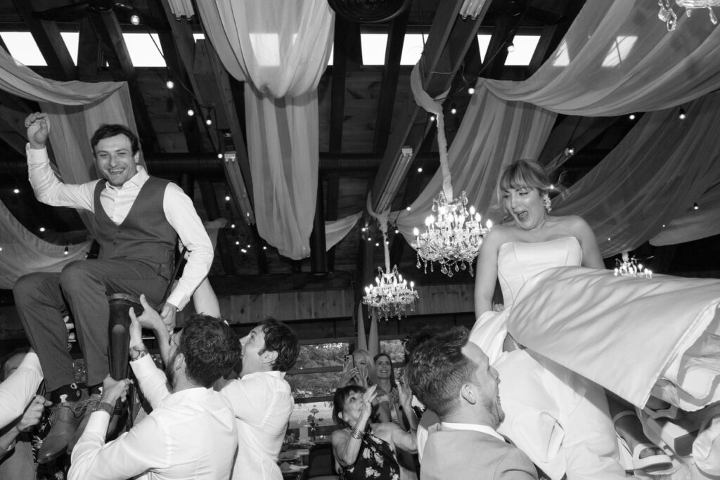 Bride and Groom being tossed in their air during hora at Kurtz Orchards Market Wedding Reception