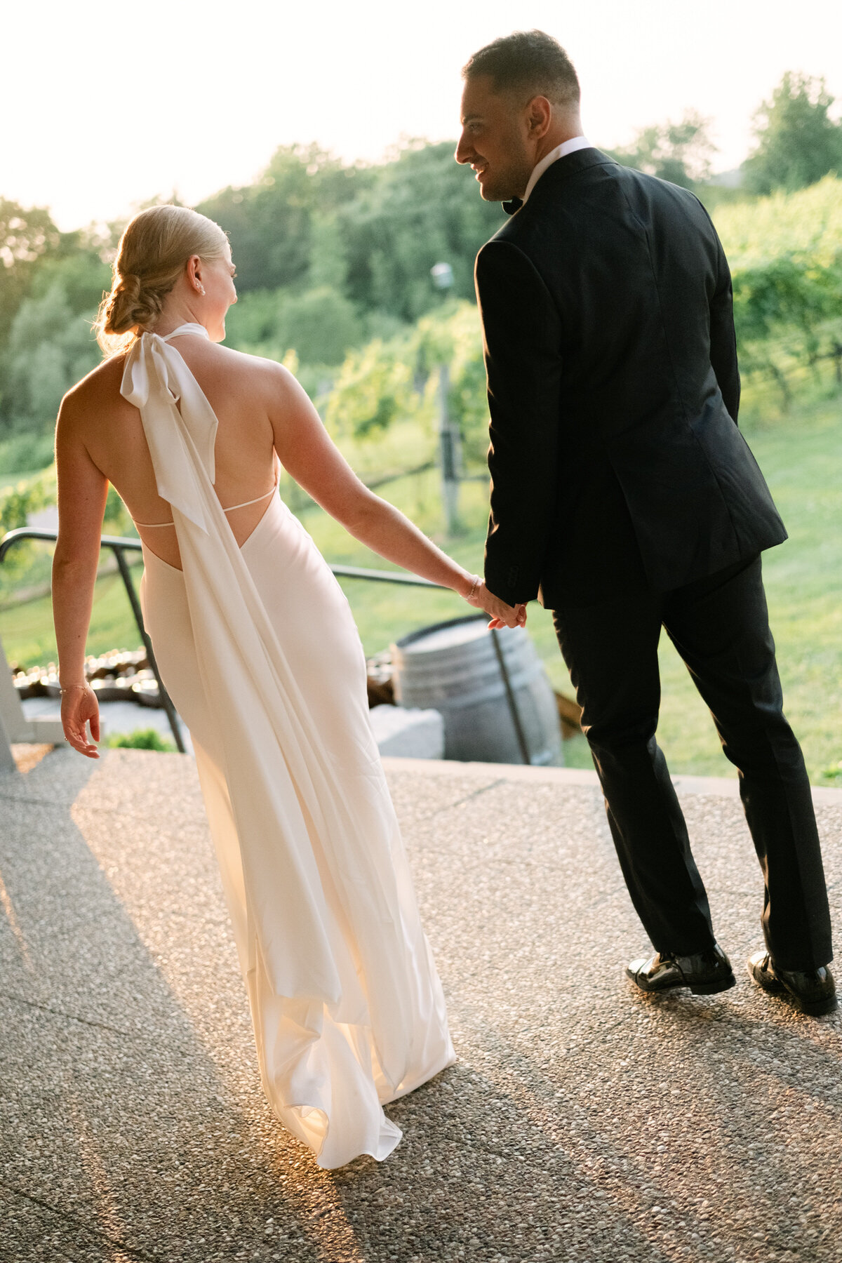 Bride and groom walking at sunset holding hands at Ravine Vineyard Estate Winery